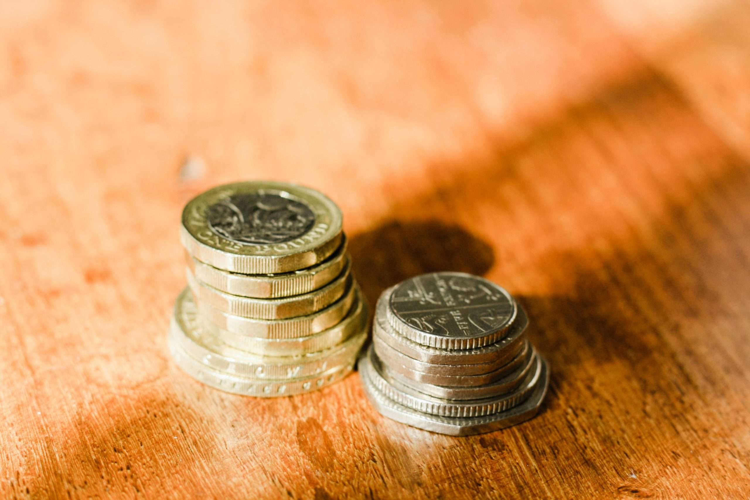 Two stacks of coins on a wooden surface.